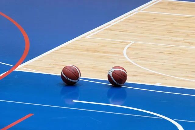 Two basketballs on a blue indoor basketball court