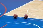 Two basketballs on a blue indoor basketball court