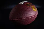 A leather American football lit against a dark background