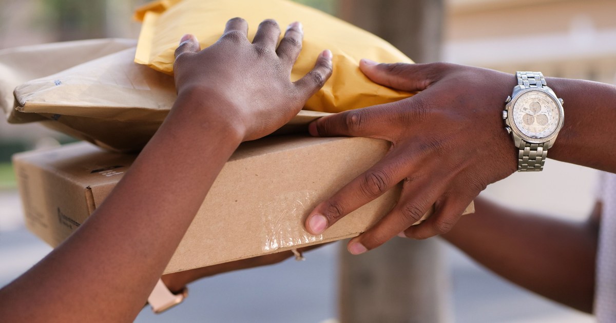 Two hands exchanging a stack of cardboard and padded shipping envelopes