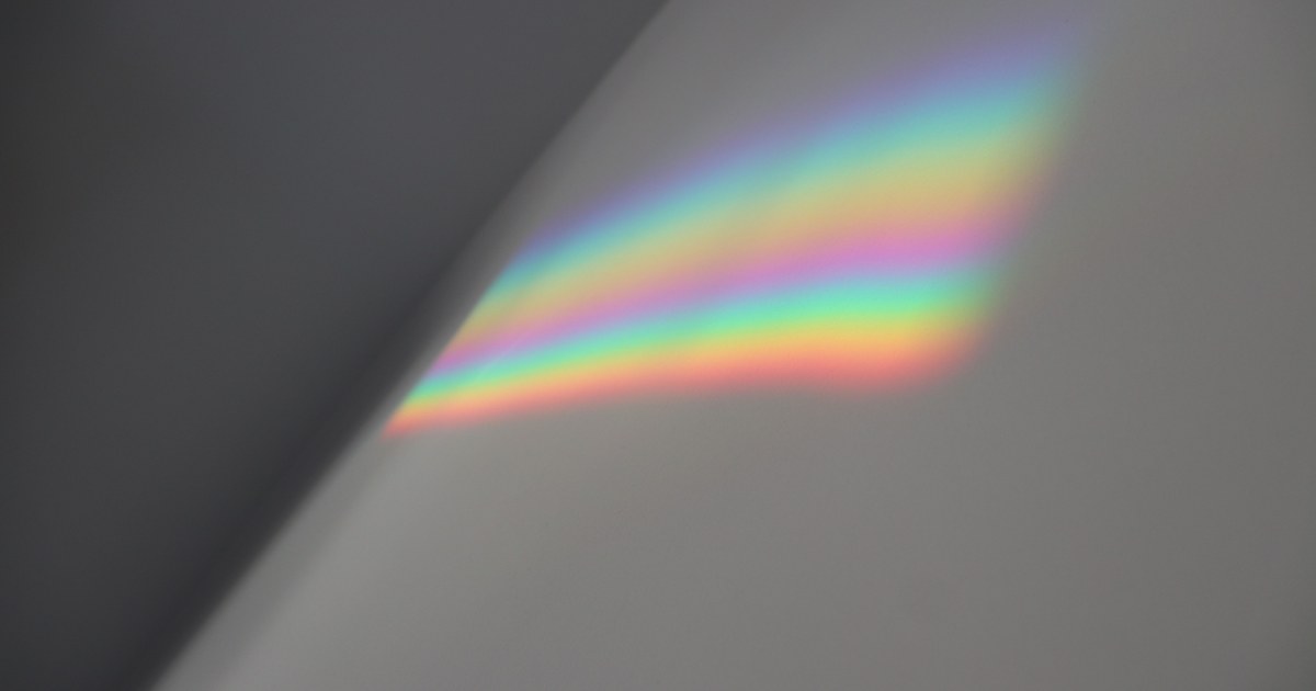 A soft rainbow light spectrum reflected on a neutral grey wall